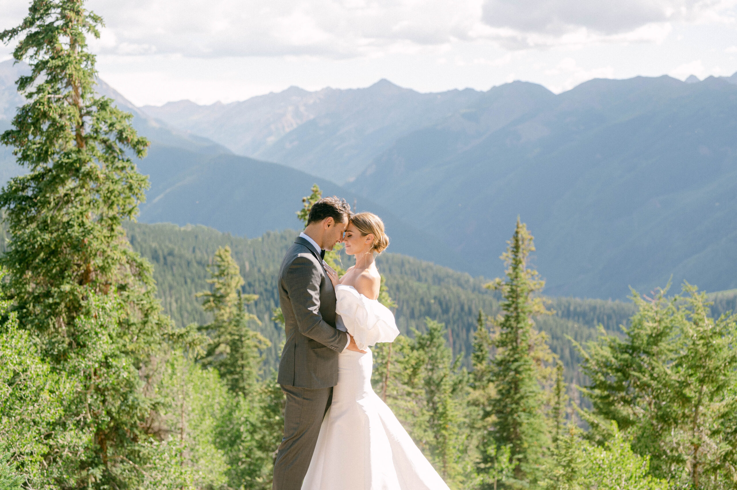 photo of bride and groom embracing with Aspen mountains as backdrop