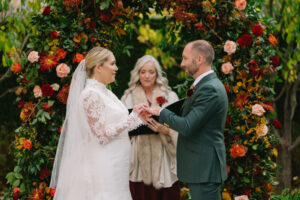 photo of bride and groom getting married before a floral altar
